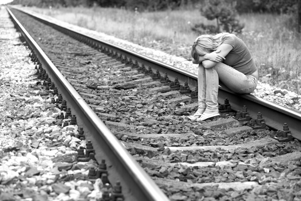 upset girl sitting on train tracks