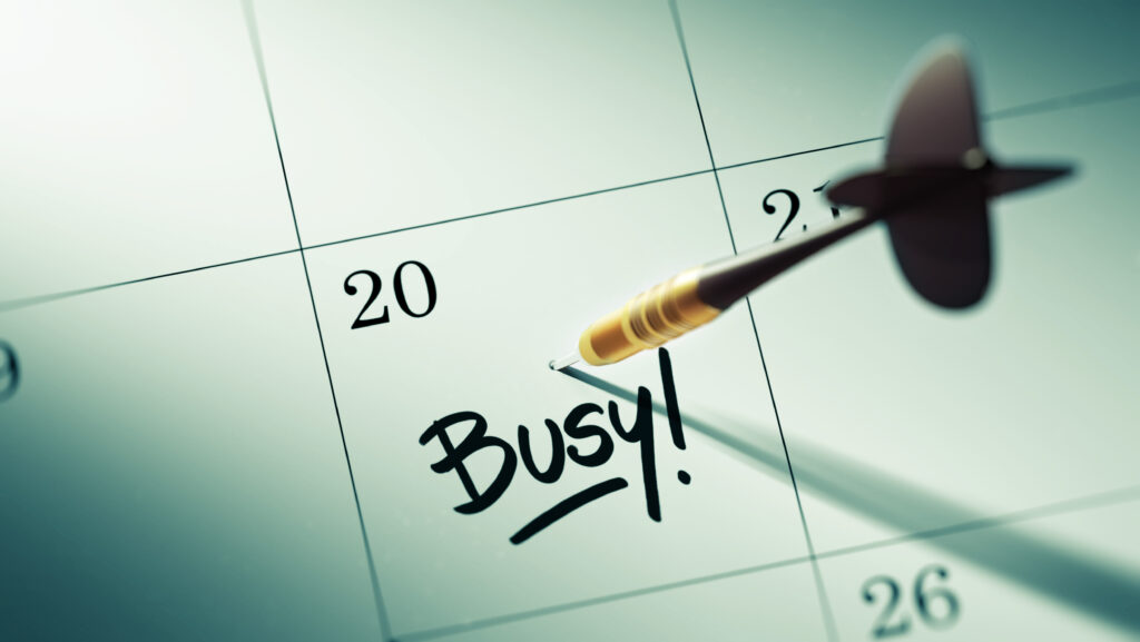 Concept image of a Calendar with a golden dart stick with the word busy