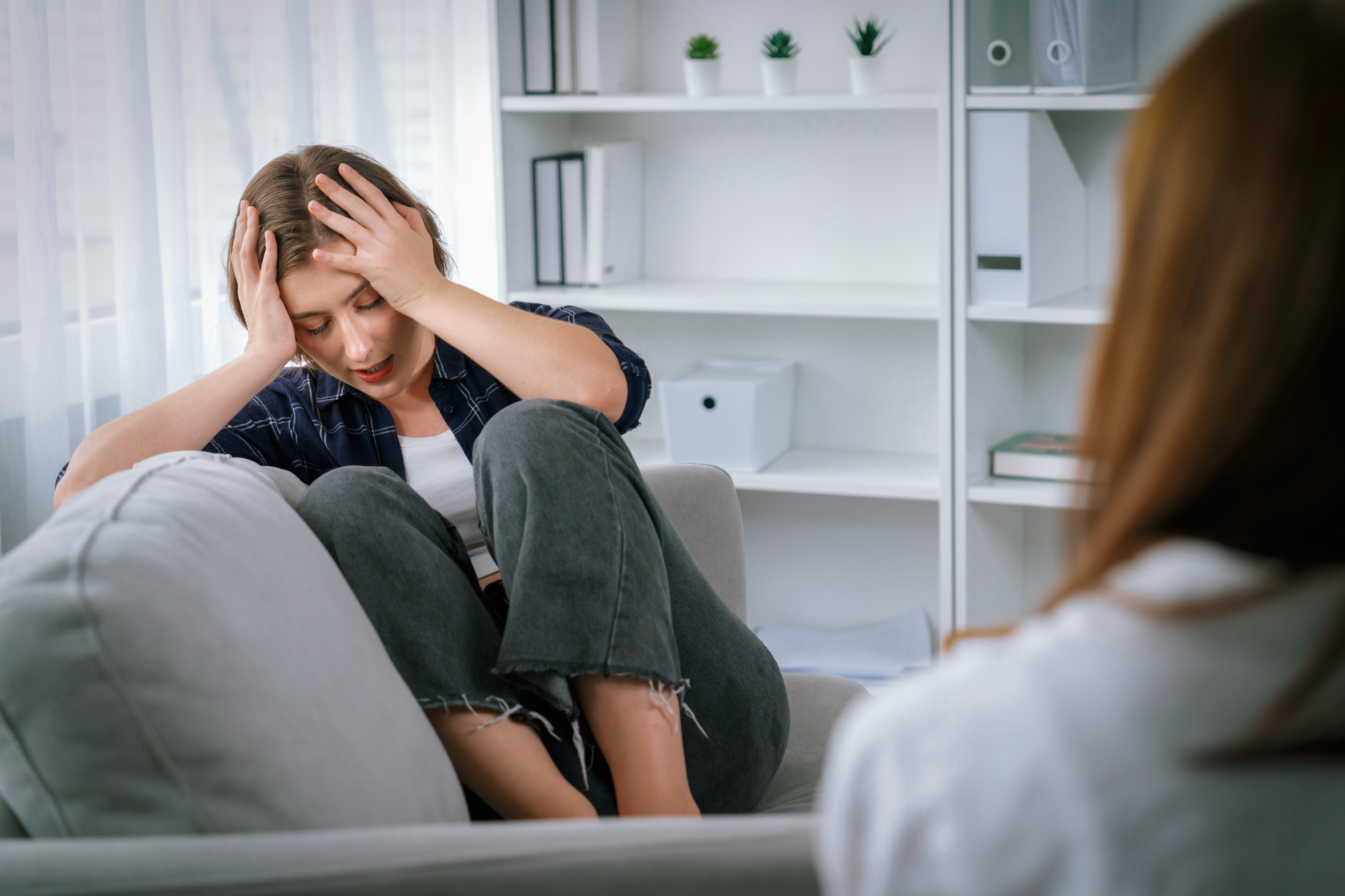 Sad PTSD woman patient in utmost therapy for mental health with psychologist, depression or grief after life failure. Frustrated trauma young woman talking to a psychologist about emotion in clinic