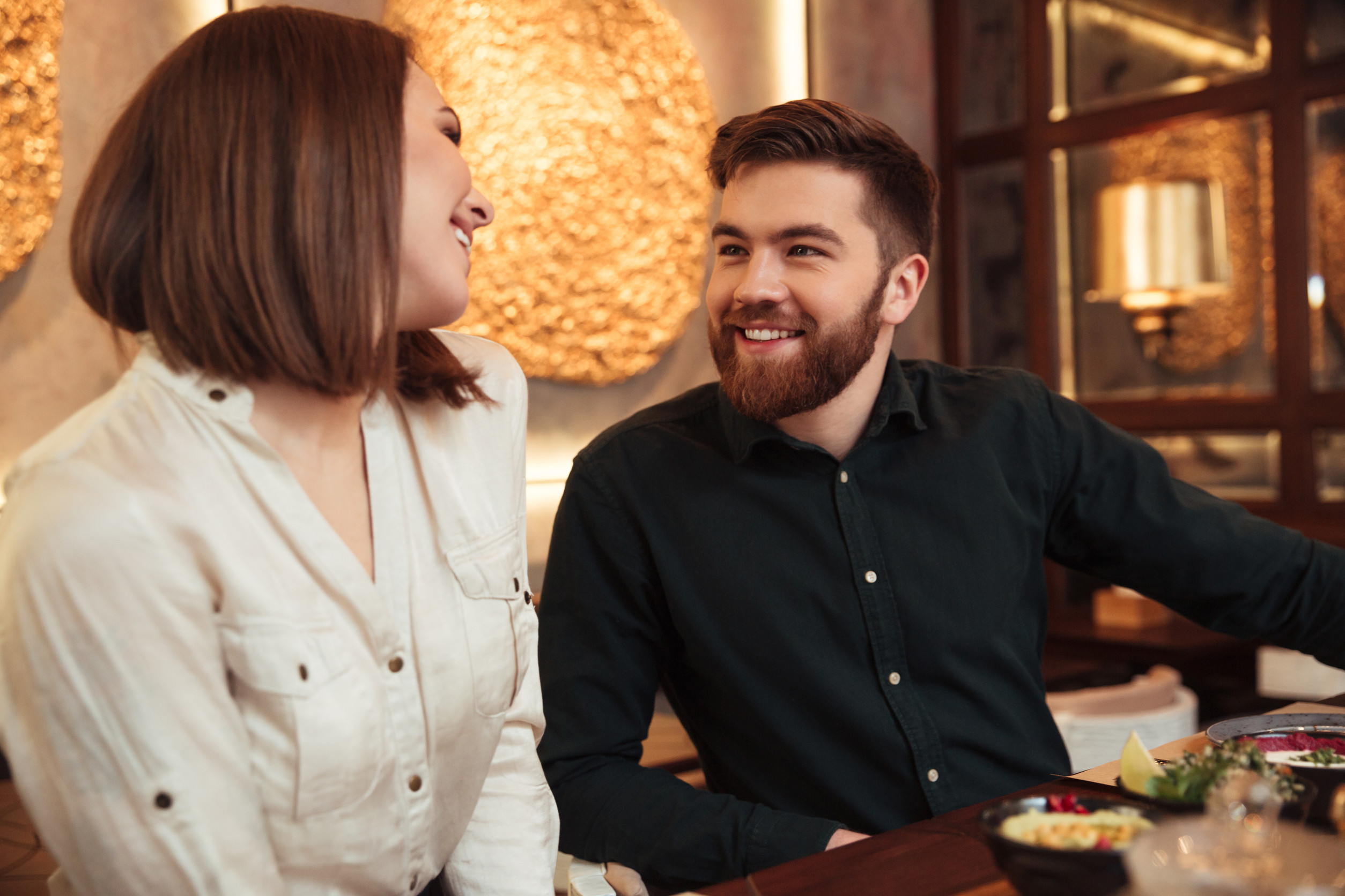 Image of happy young loving couple sitting in cafe and looking at each other.