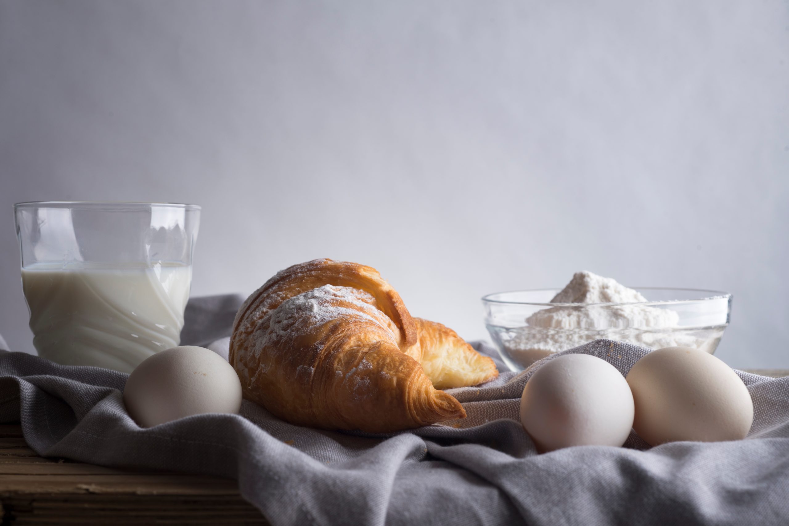 Still life of croissants, eggs, milk and flour. Rustic style.