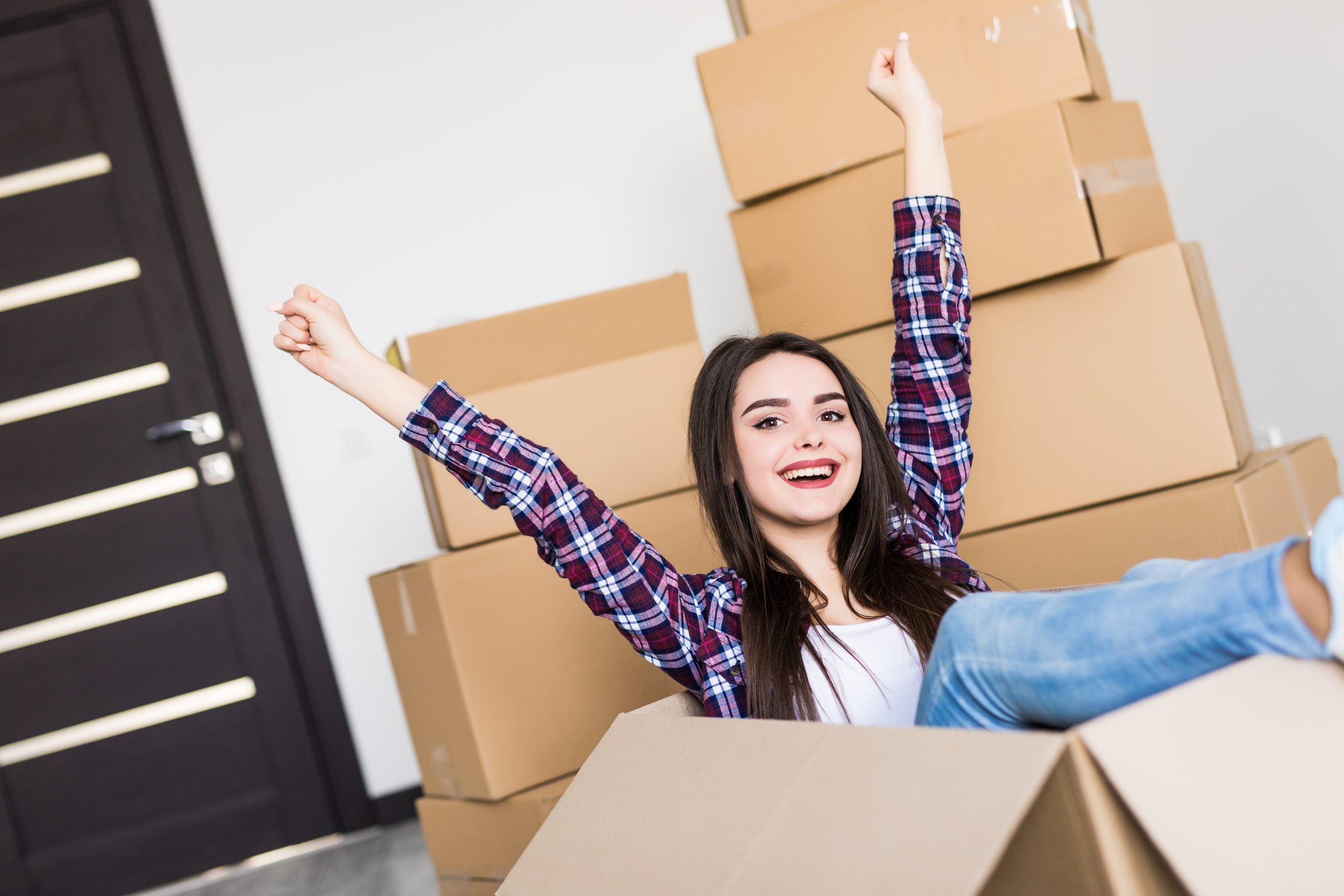 Woman sitting inside a cardboard box while packing