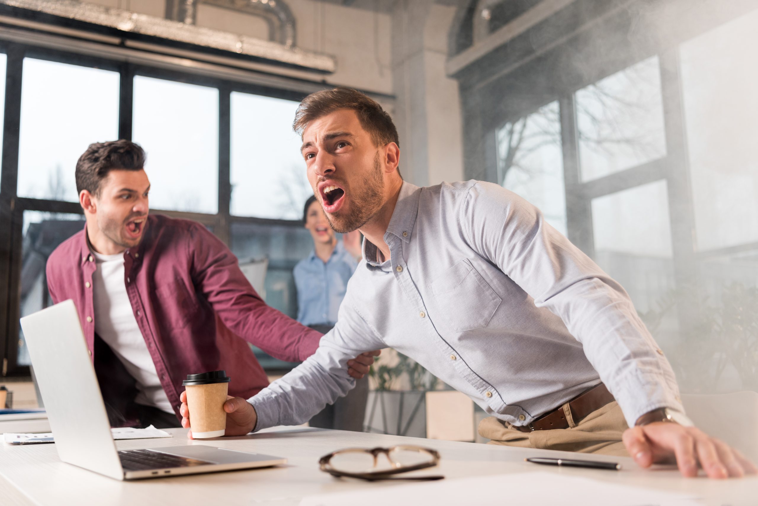 scared businessman holding paper cup and yelling near colleagues in office with smoke during fire