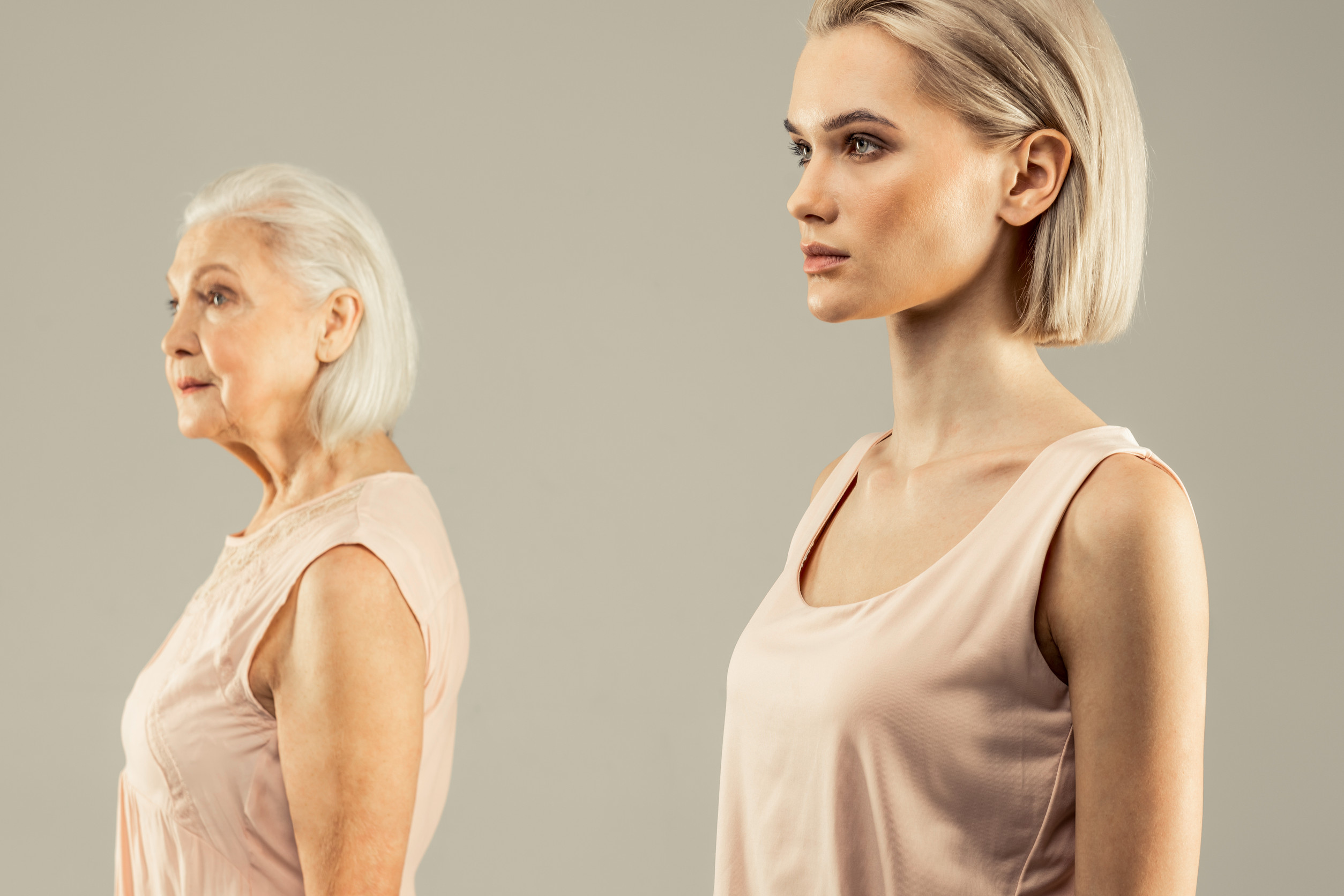 So young. Beautiful blonde woman looking in front of her while standing against grey background