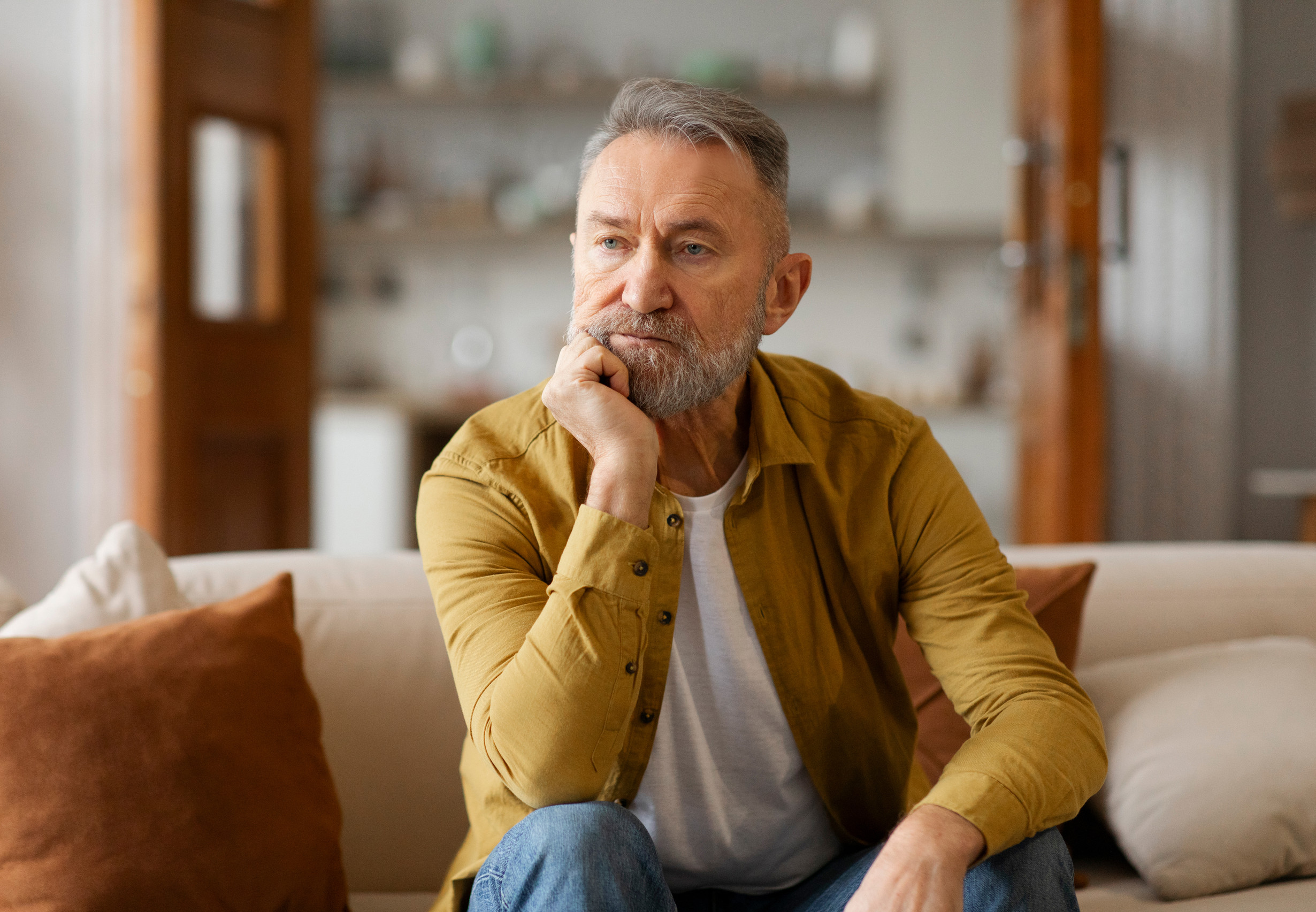 Portrait of thoughtful senior man touching chin, looking away, thinking of problems difficulties, retirement life concept